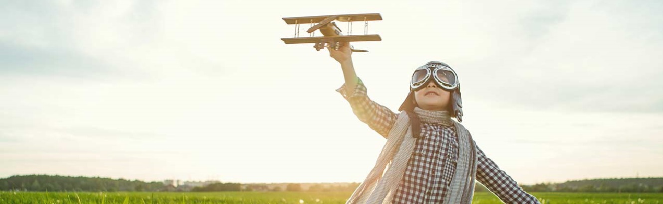 Child in field holding toy airplane.